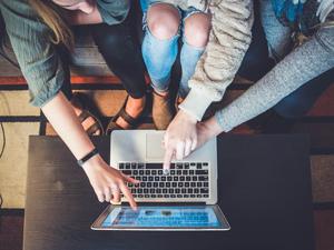 students pointing to laptop screen